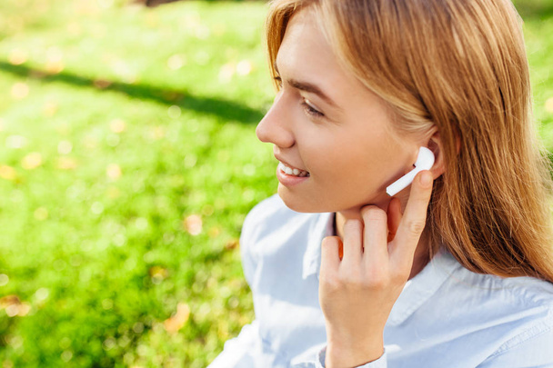 Joven mujer de negocios escuchando música a través de auriculares inalámbricos al aire libre
 - Foto, imagen