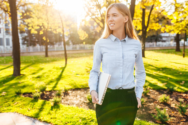 Изображение молодой девушки, гуляющей в парке, с ноутбуком
. - Фото, изображение