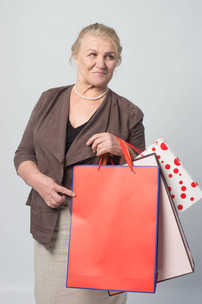 Alışveriş torbaları tutan bir yaşlı kadın - Fotoğraf, Görsel