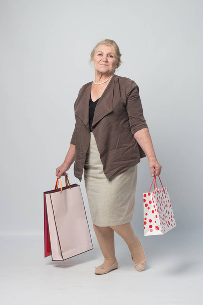 an old woman holding shopping bags - Fotó, kép
