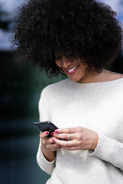 Portrait of attractive afro woman using mobile phone in the street. Business woman concept - Foto, Imagem