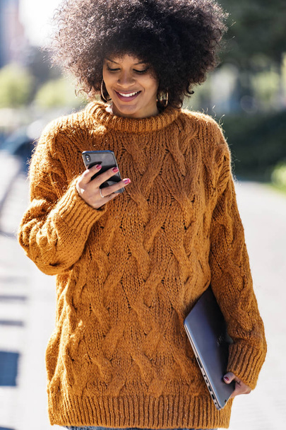 Portrait of attractive afro woman using mobile phone in the street. Business woman concept - Foto, immagini