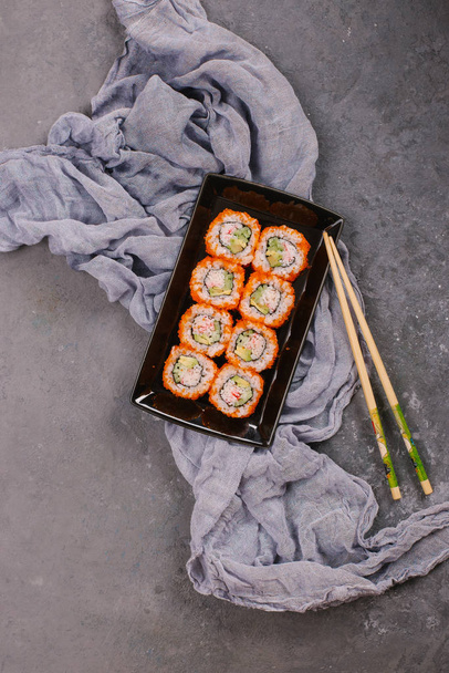 Top view of fresh traditional japanese rolls on black plate with chopsticks on concrete background - Valokuva, kuva