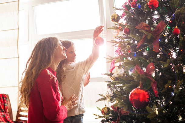 Mom and daughter decorate the Christmas tree - Foto, imagen