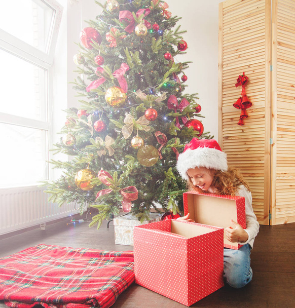 Child with gift near christmas tree - Фото, изображение
