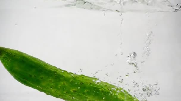 Groene cucumder valt in water met spatten en bubbels - Video