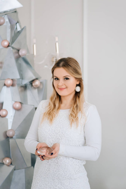 Merry Christmas and happy New year.  Beautiful girl near modern silver metal Christmas tree - Photo, Image