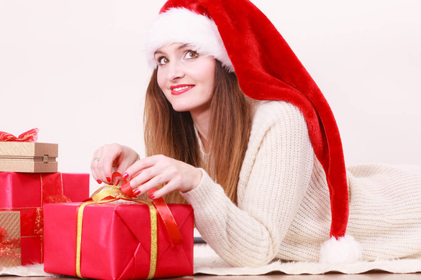 Christmas winter happiness concept. Woman wearing santa helper hat with many presents red golden gift boxes - Zdjęcie, obraz