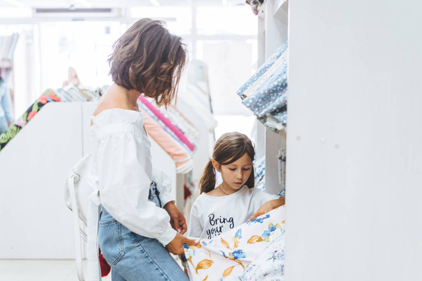 Mom and daughter in the fabric store choose fabric - Zdjęcie, obraz