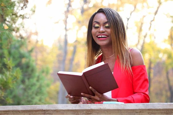 schöne junge afrikanische Mädchen lesen Buch über Herbstblätter Hintergrund in par - Foto, Bild