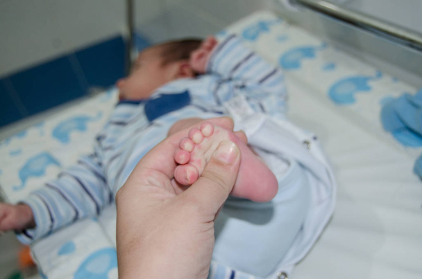 Moeder masseren weinig pasgeboren baby voet, close-up - Foto, afbeelding