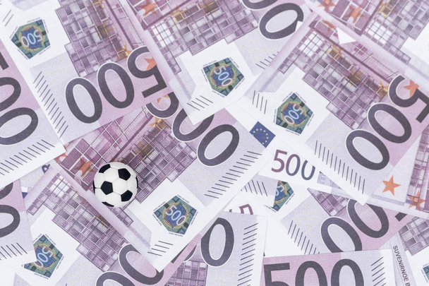 small black and white soccer ball on the background of paper money with a face value of five hundred euro - Fotografie, Obrázek