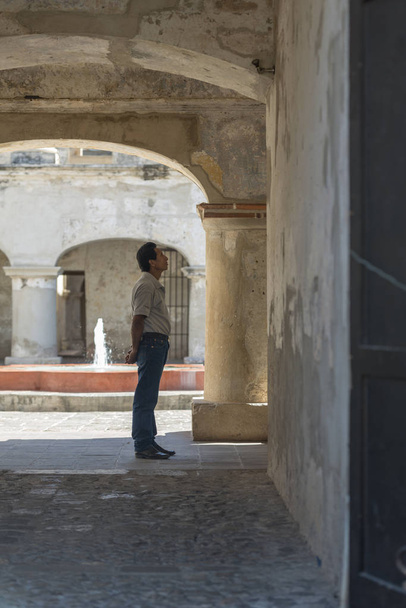 ANTIGUA, GUATEMALA - FEBRUARY 24, 2018: Unidentified man looks at the architecture of the popular colonial town of Antigua, Guatemala. - Photo, image