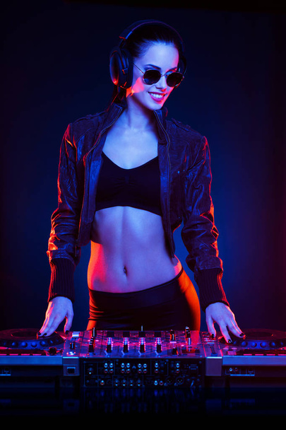 Hot DJ woman in party outfit, colorful stage lighting. - Photo, Image