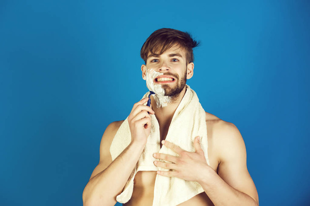macho smiling with naked torso shaving beard with safety razor - 写真・画像