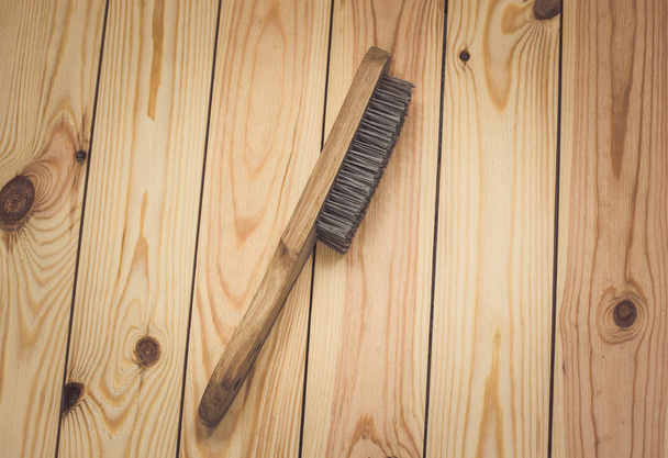 Wire brush with wooden handle on raw wooden background. - Foto, imagen