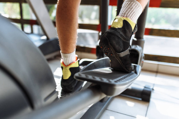 feet close-up, man riding a sports bike in the gym, morning training - Фото, изображение