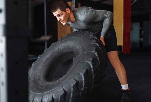 A man raises a big wheel in the gym - Foto, afbeelding