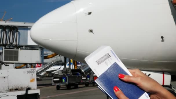 AEROPUERTO BORYSPIL, UCRANIA - 24 DE OCTUBRE DE 2018: Primer plano, manos femeninas sosteniendo billetes de avión, tarjeta de embarque y pasaporte en el aeropuerto, en el fondo de la aeronave
 - Metraje, vídeo