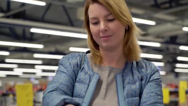 Young woman shopping in hypermarket. Choosing shoes in a shop - Materiał filmowy, wideo
