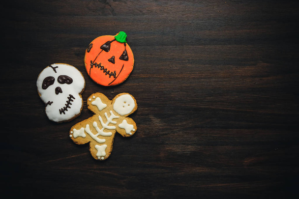 Galletas caseras divertidas de la galleta del jengibre para la vista superior de Halloween en la mesa de madera oscura
 - Foto, imagen