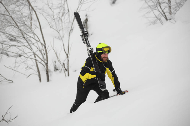 Szczęśliwe spacery uśmiechniętych narciarzy w górach w głębokim śniegu po freeride narciarstwo alpejskie z nartach na ramieniu - Zdjęcie, obraz
