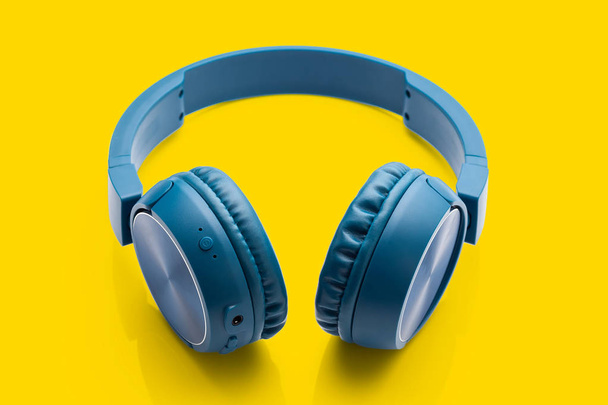 bluetooth auriculares azules en el equipo de fondo amarillo paquete de estudio
 - Foto, Imagen