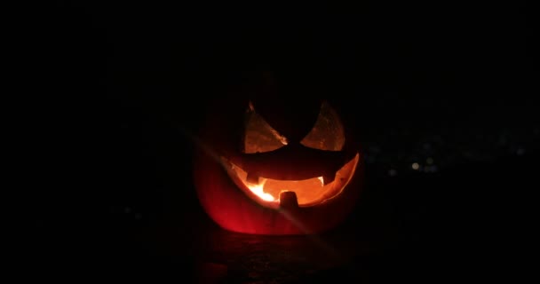 Horror Halloween concept. Close up view of scary dead Halloween pumpkin glowing at dark background. Rotten pumpkin head. Selective focus - Footage, Video