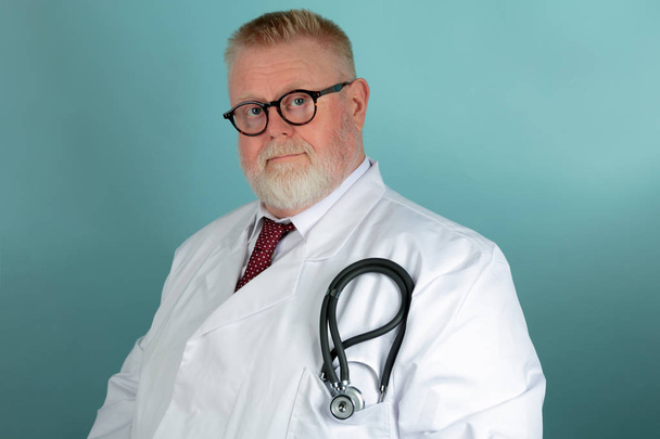Olgunlaştı, kendinden emin beyaz erkek tıp doktoru stetescope ve mavi zemin üzerine beyaz önlük - Fotoğraf, Görsel
