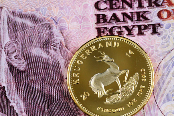 A close up image of a South African krugerrand with an Egyptian ten pound bill  - Photo, Image