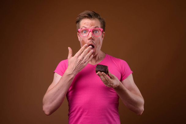 Young handsome man wearing pink shirt and eyeglasses against bro - Foto, afbeelding