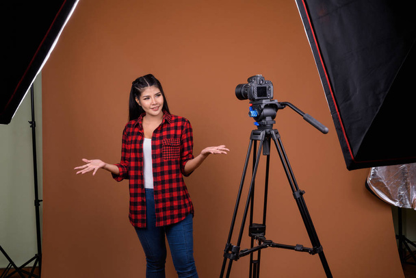 Estudio disparo de joven hermosa mujer asiática con camisa a cuadros rojo sobre fondo marrón
 - Foto, Imagen