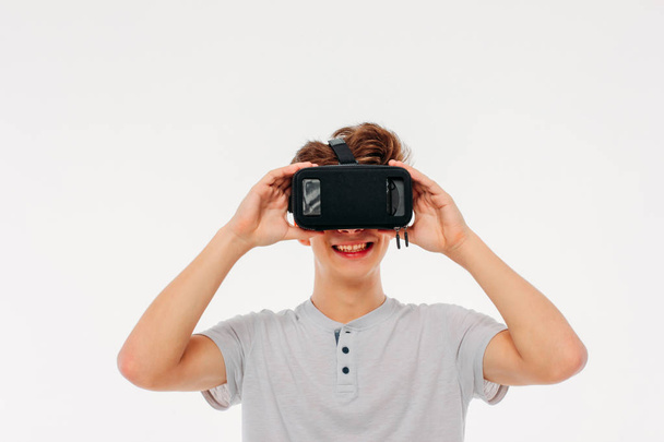 Jeune homme adolescent étudiant portant des lunettes de réalité virtuelle sur fond blanc
 - Photo, image