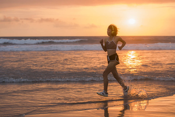 silhouette of fit and athletic Asian Chinese sporty woman running on beautiful beach doing jogging workout on sunset in fitness healthy lifestyle and summer outdoors activity concept - Foto, imagen