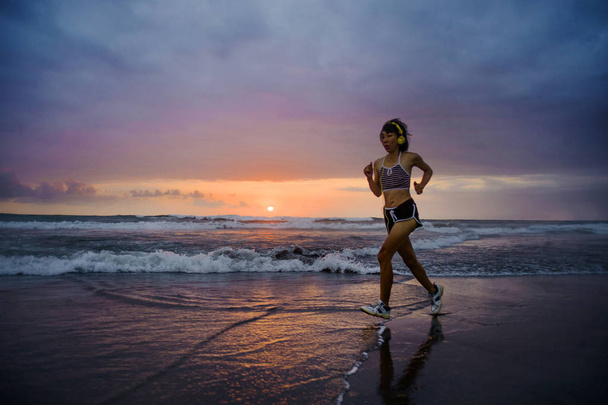 silhouette of fit and athletic Asian Chinese sporty woman running on beautiful beach doing jogging workout on sunset in fitness healthy lifestyle and summer outdoors activity concept - Foto, Bild