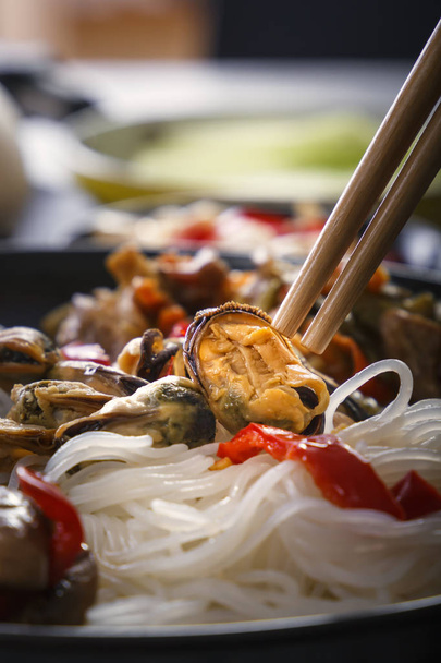 Mussel on the background of a dish with traditional Asian rice noodles. Close-up - Foto, Bild
