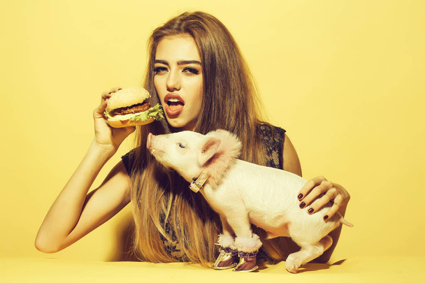 Girl eating burger with pig - Foto, afbeelding