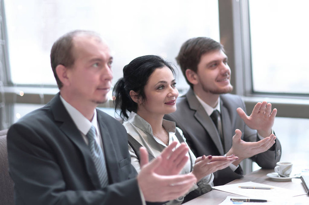 close up.business team applauding the speaker, sitting in the workplace. - Photo, Image