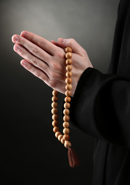 Priest holding rosary, on black background - Photo, Image