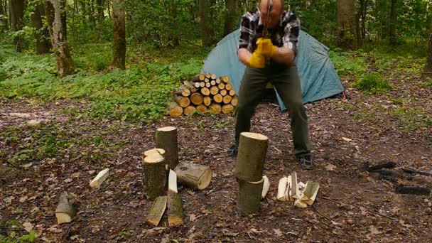 Człowieku turystycznych w żółty rękawice hopping drewna w pobliżu camping namiot. Zwolnionym tempie - Materiał filmowy, wideo