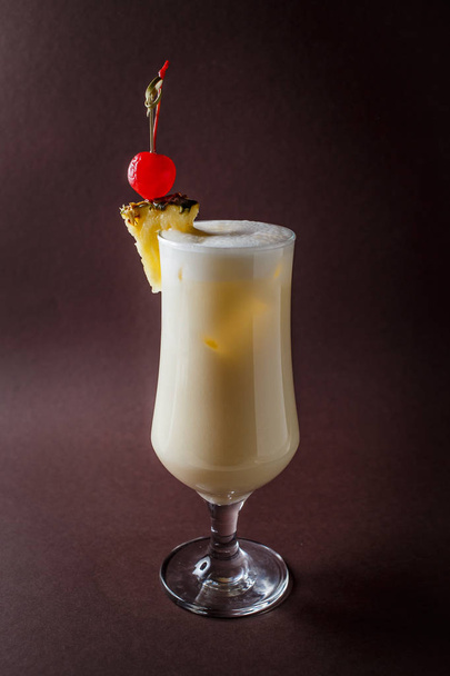 Glass of pina colada with berry and pineapple on elegant dark brown background. - Zdjęcie, obraz