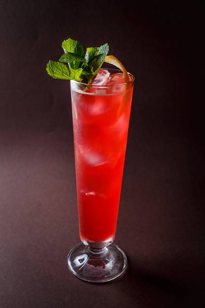 Glass of red alcohol cocktail with mint and orange on elegant dark brown background. - Zdjęcie, obraz