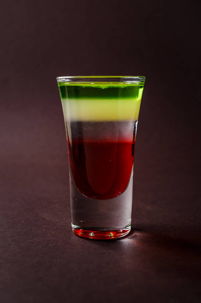 Alcoholic shot glass with grenadine, absent on elegant dark brown background. - Foto, Imagen