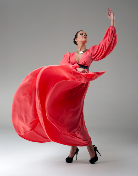 girl in a long red dress dancing - Фото, изображение