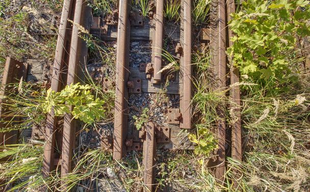 Velho trilho abandonado e parafuso de uma ferrovia. Rusty trem ferroviário detalhe, dormentes oleados e pedras entre a via férrea
  - Foto, Imagem