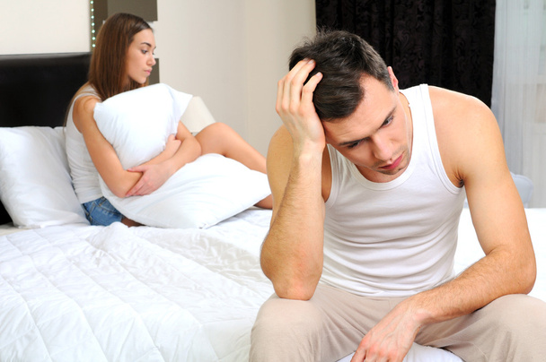 Homem perturbado ter problema sentado na cama com sua namorada
 - Foto, Imagem
