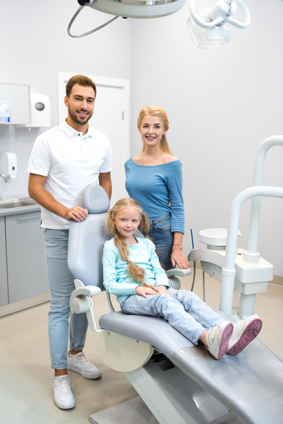 schöne junge Familie blickt in Zahnarztpraxis in die Kamera - Foto, Bild