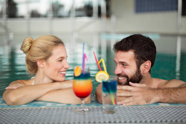 Cheerful happy couple enjoying together in swimming pool at spa center - Фото, изображение