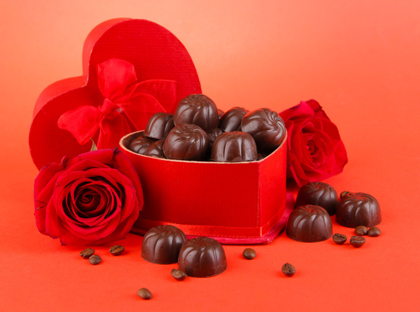 Dulces de chocolate en caja de regalo, sobre fondo rojo
 - Foto, imagen