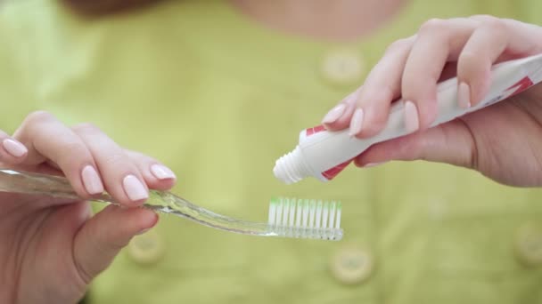 Feche as mãos de mulher que apertam pasta de dentes na escova de dentes. Conceito de higiene oral
 - Filmagem, Vídeo